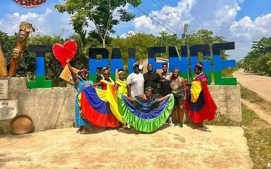 Palenqueras con trajes típicos frente a las letras de Palenque