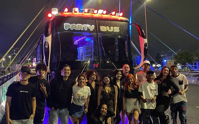 Grupo frente al Party Bus iluminado de noche